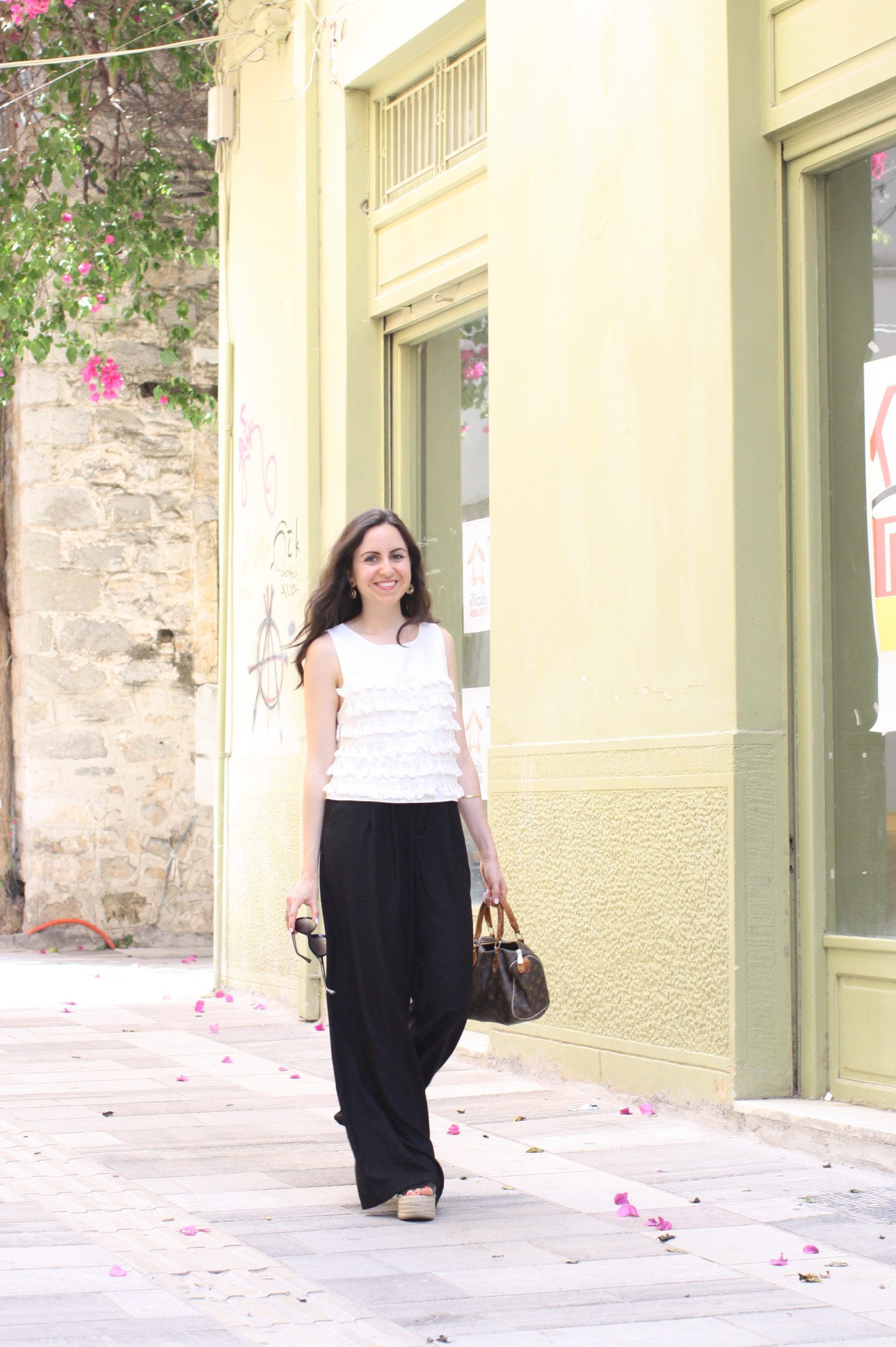 Yana Puaca of NoMad Luxuries wearing a white tassel top and black palazzo pants with asos flatform shoes and a louis vuitton purse