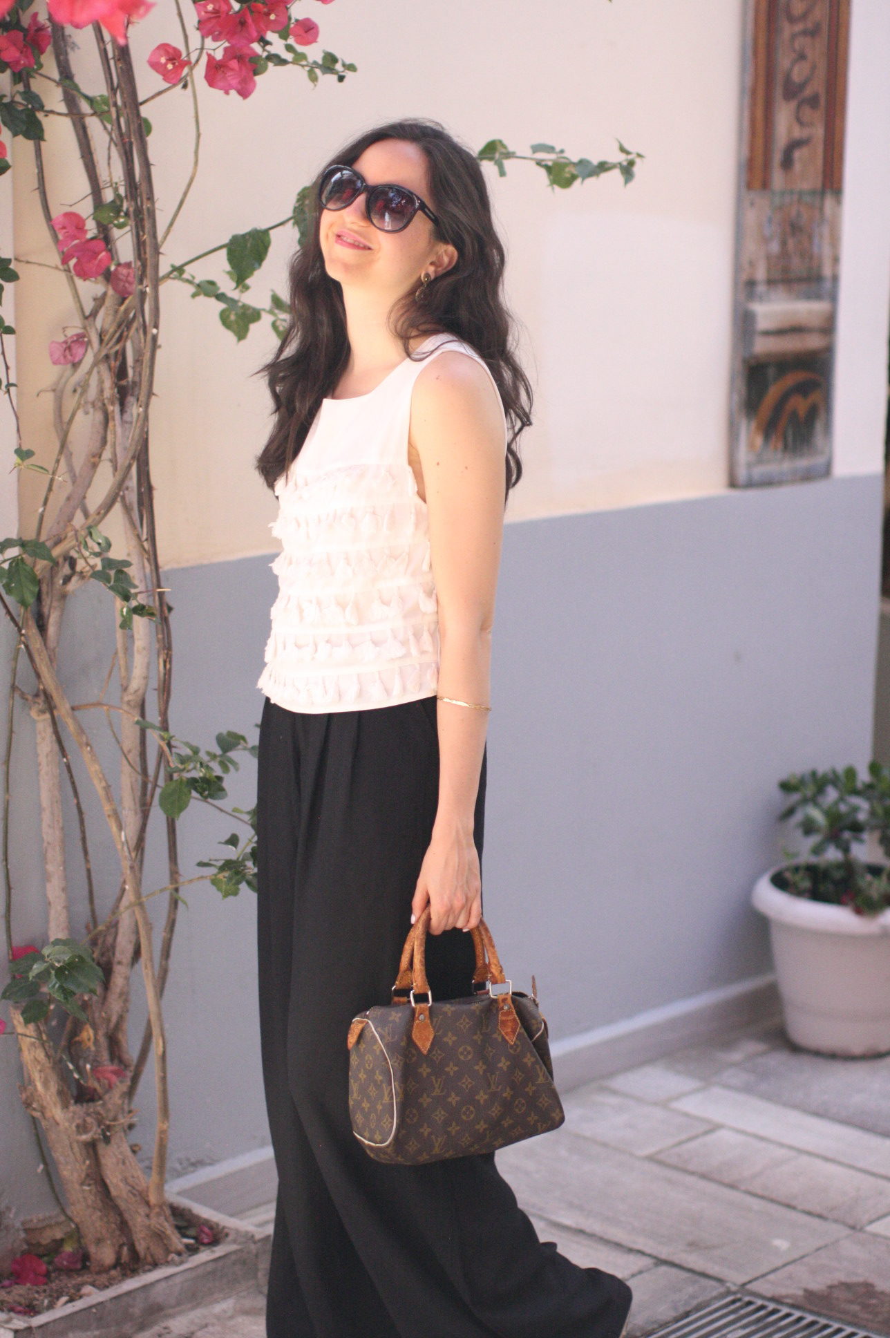 Yana Puaca of NoMad Luxuries wearing a white tassel top and black palazzo pants with asos flatform shoes and a louis vuitton purse and vintage gold jewelry