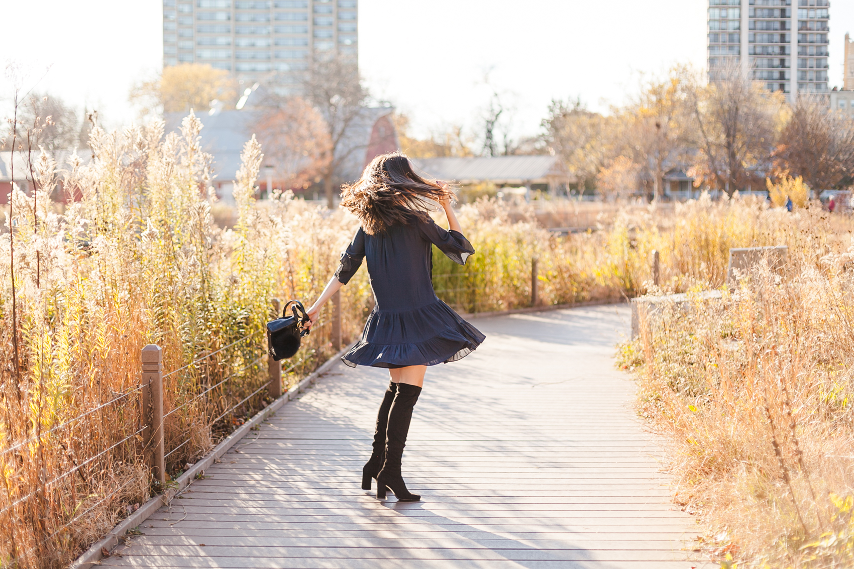 Yana Frigelis of NoMad Luxuries wearing a navy boho inspired dress from loft and over the knee boots for fall in chicago