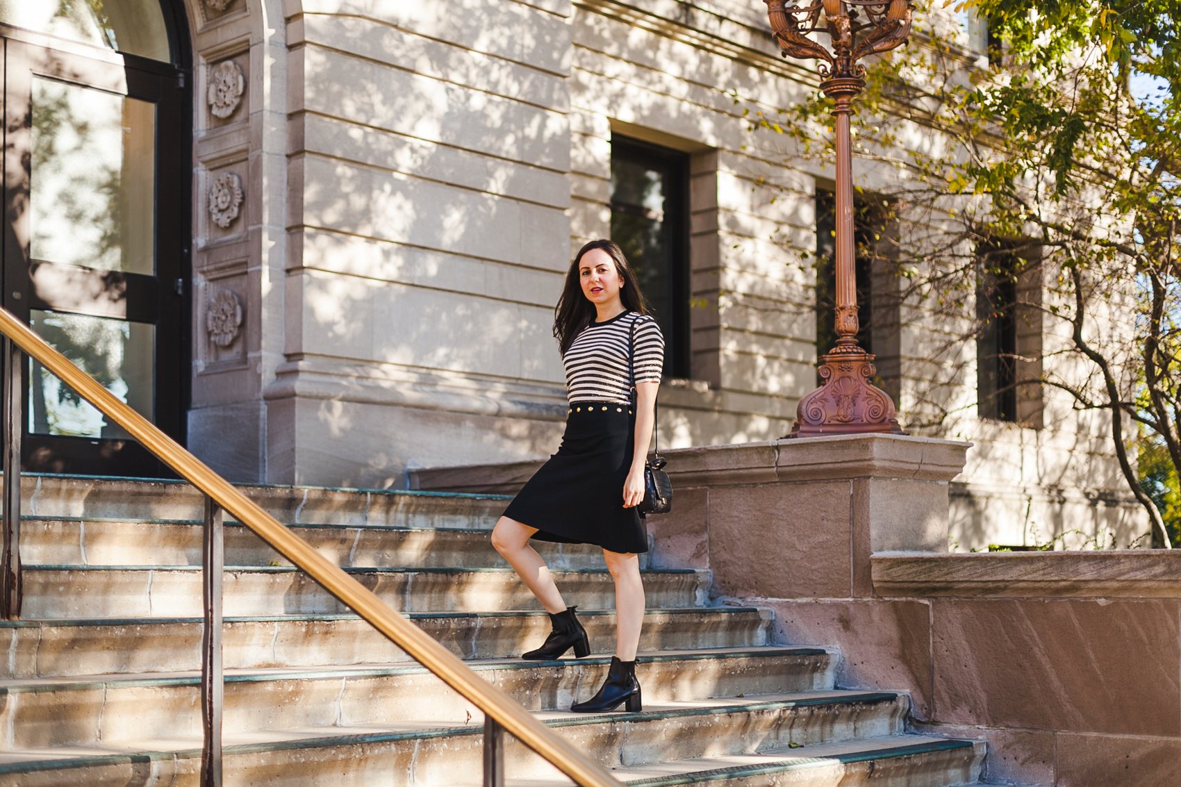 Yana Frigelis of NoMad Luxuries wearing a Sandro striped dress in black and gold in Chicago