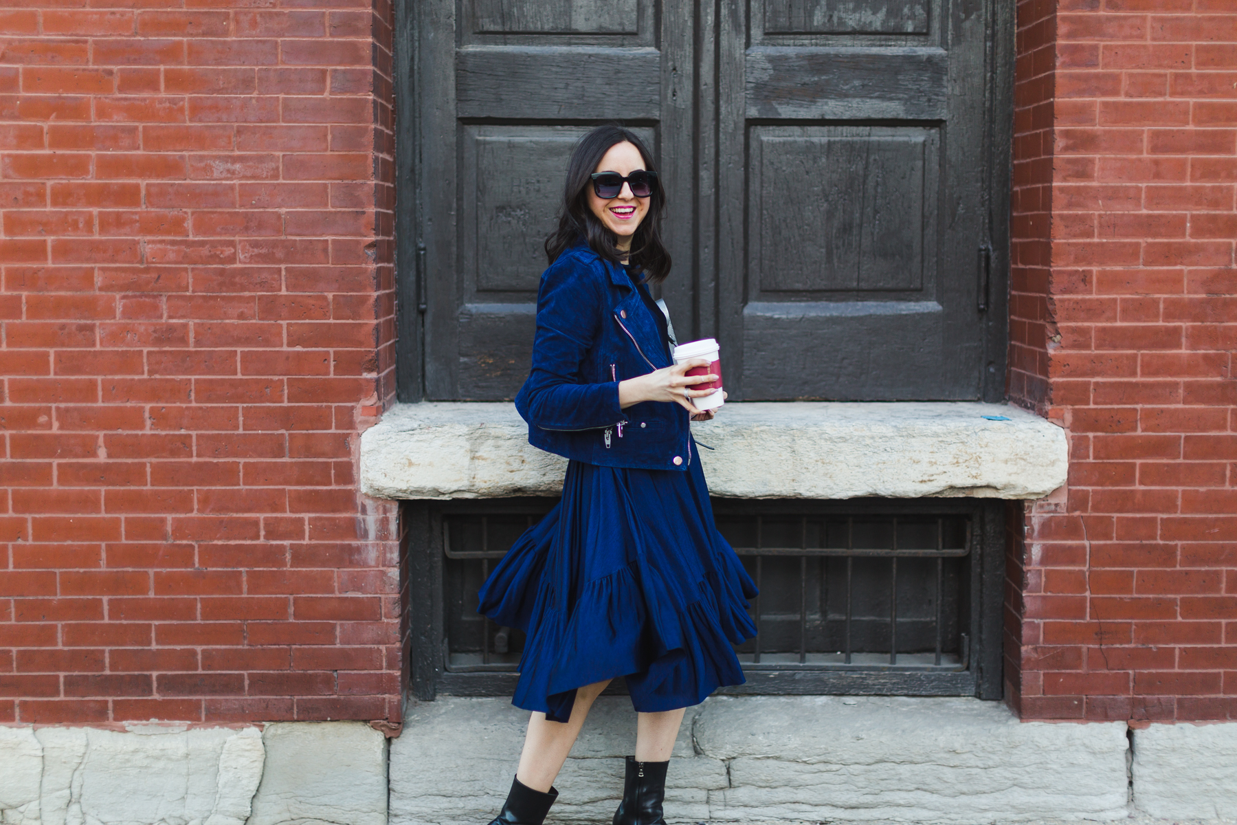 Yana Frigelis of NoMad Luxuries wearing a navy zara pleated dress with a navy moto jacket from tj maxx for spring