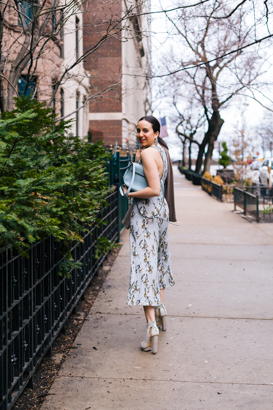 Yana Frigelis of NoMad Luxuries wearing a floral culotte jumpsuit in nuetral colors and accessories for Spring
