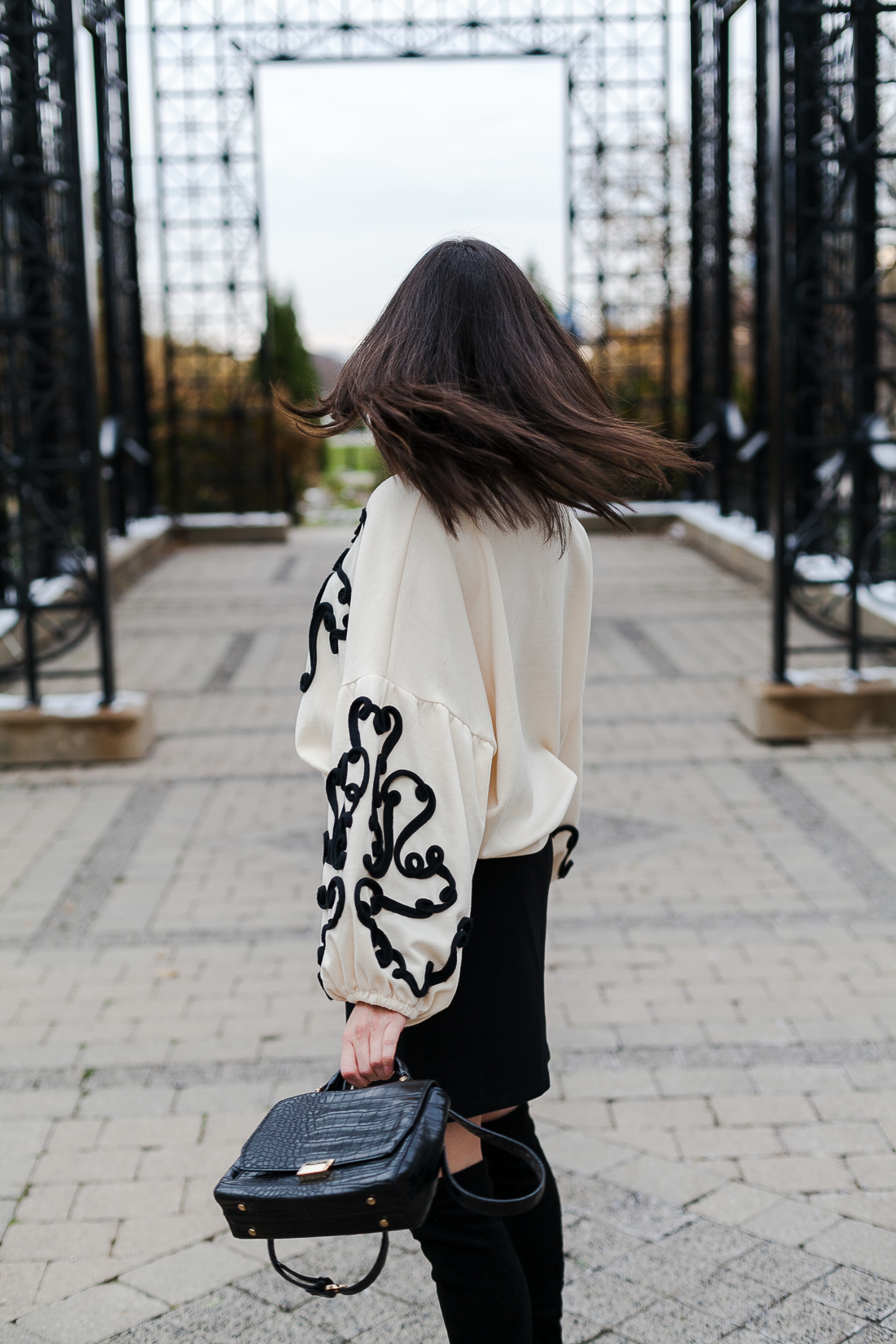 Yana Frigelis of NoMad Luxuries wearing an embroidered sweatshirt from zara and over the knee boots for a simple yet statement making outfit 