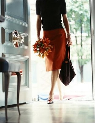 Nomad Luxuries; a woman walking in holding a bouquet a flowers. 
