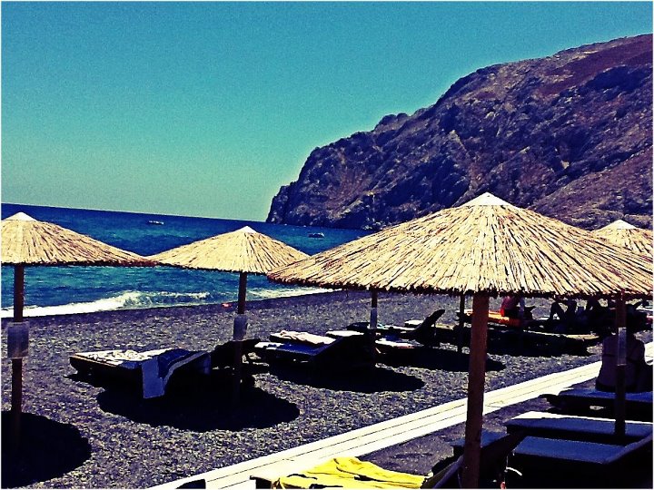Nomad Luxuries photo of all the umbrellas on the sunny beach in Santorini